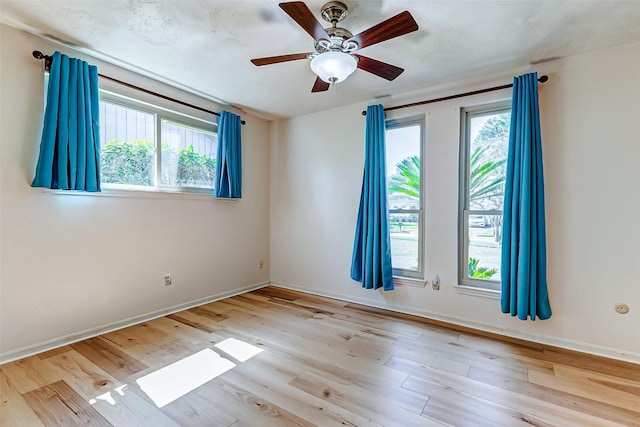 empty room featuring a ceiling fan, baseboards, and wood finished floors