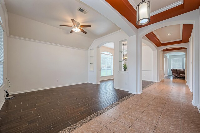 spare room with baseboards, visible vents, ceiling fan, wood finished floors, and crown molding