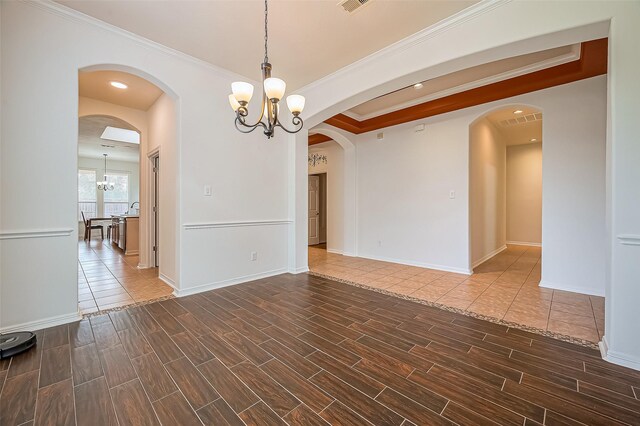 unfurnished room featuring an inviting chandelier, wood tiled floor, arched walkways, and crown molding