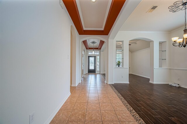 entryway featuring ornamental molding, arched walkways, a chandelier, and baseboards