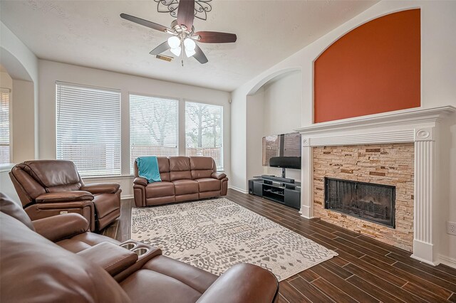 living room with wood tiled floor, ceiling fan, a stone fireplace, and baseboards