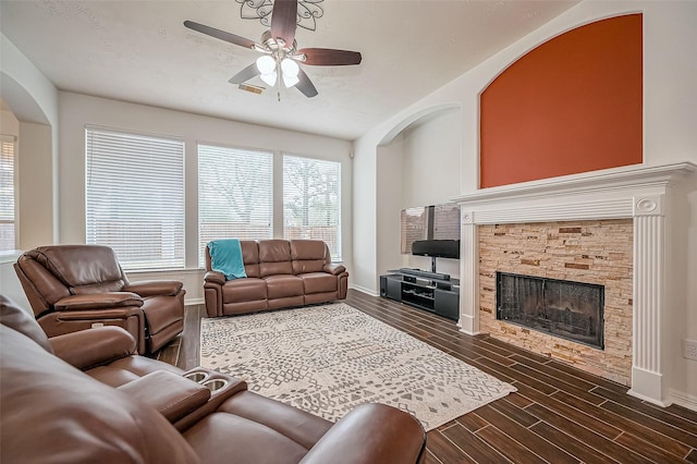 10714 Barker Lake Ct, Cypress, TX 77433 - living room with ceiling fan, arched walkways, a fireplace, dark wood-type flooring, and baseboards