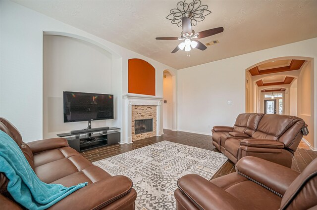 living room with dark wood finished floors, a fireplace, visible vents, a ceiling fan, and baseboards