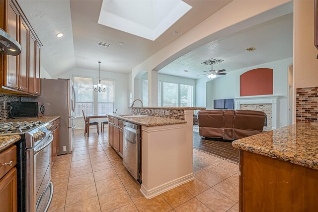 kitchen with a healthy amount of sunlight, stainless steel appliances, decorative backsplash, and ceiling fan with notable chandelier