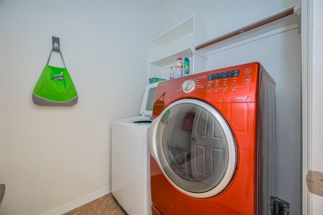 clothes washing area featuring baseboards, laundry area, washing machine and clothes dryer, and tile patterned floors