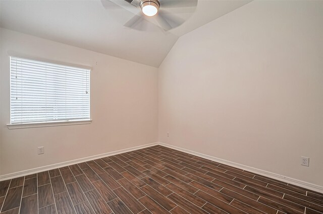 spare room featuring lofted ceiling, dark wood-type flooring, a ceiling fan, and baseboards