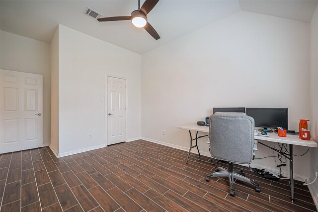 home office featuring baseboards, visible vents, dark wood finished floors, a ceiling fan, and vaulted ceiling