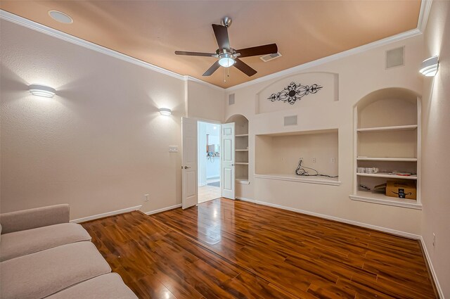 unfurnished living room with crown molding, built in shelves, arched walkways, and wood finished floors