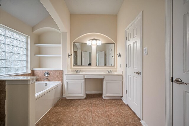 bathroom with tile patterned flooring, a garden tub, a sink, and double vanity