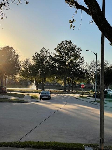 view of road featuring sidewalks, traffic signs, curbs, and street lights