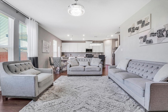 living room featuring dark wood-type flooring, recessed lighting, and a chandelier