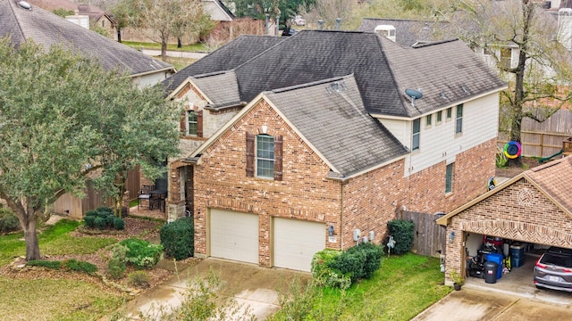 exterior space with brick siding, roof with shingles, concrete driveway, fence, and a garage