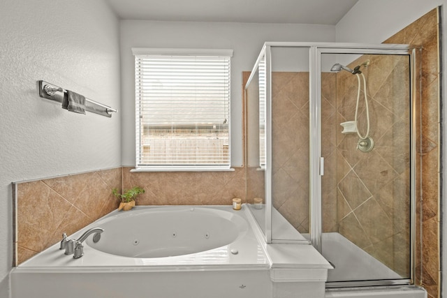 bathroom with a stall shower, a textured wall, and a whirlpool tub