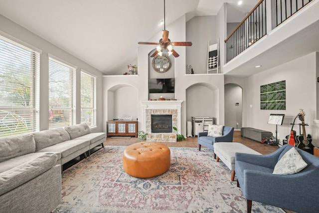 living area with high vaulted ceiling, tile patterned flooring, a fireplace, and arched walkways