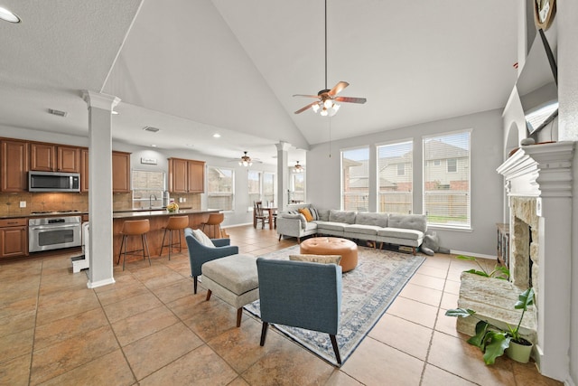 living area with light tile patterned floors, a ceiling fan, decorative columns, and a healthy amount of sunlight