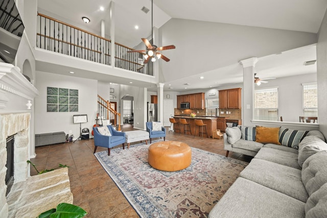 living room with visible vents, a premium fireplace, a ceiling fan, light tile patterned flooring, and stairs