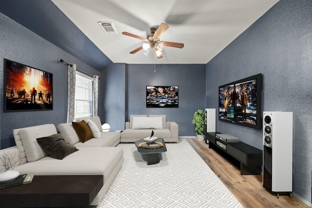 living room with visible vents, a textured wall, a ceiling fan, wood finished floors, and baseboards