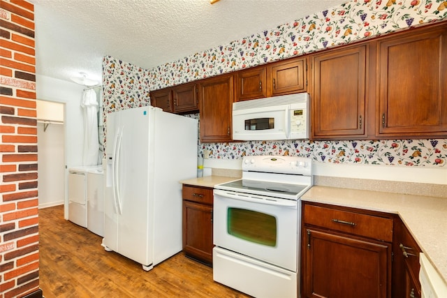 kitchen featuring a textured ceiling, white appliances, light wood-style floors, light countertops, and washer and clothes dryer