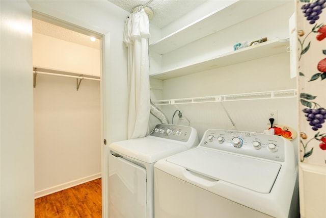 clothes washing area featuring laundry area, baseboards, wood finished floors, independent washer and dryer, and a textured ceiling