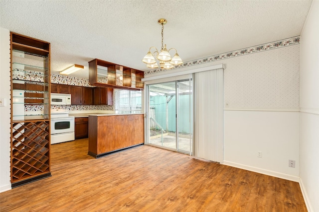 kitchen featuring wainscoting, a textured ceiling, light wood-type flooring, white appliances, and wallpapered walls