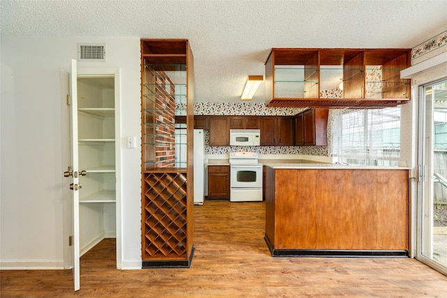 kitchen featuring a textured ceiling, white appliances, visible vents, light countertops, and light wood-type flooring