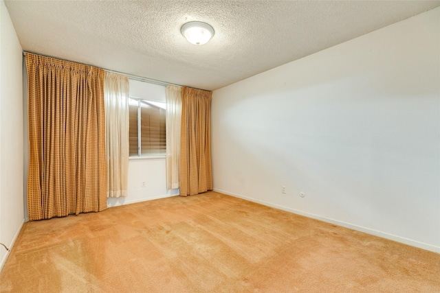 spare room featuring carpet flooring, a textured ceiling, and baseboards