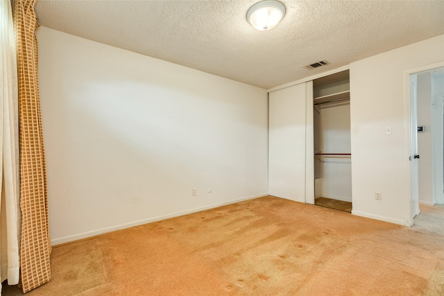 unfurnished bedroom featuring a textured ceiling, visible vents, baseboards, a closet, and carpet