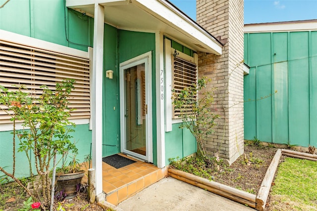 view of exterior entry with a chimney and brick siding