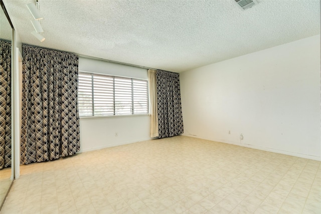 spare room with visible vents, a textured ceiling, and tile patterned floors