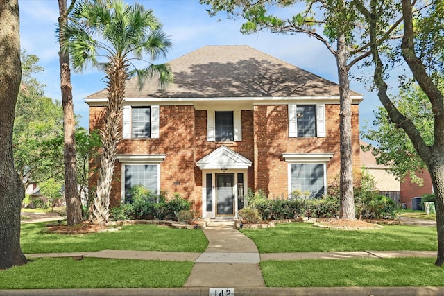 colonial house with brick siding, roof with shingles, and a front yard