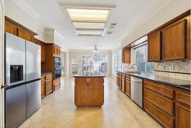 kitchen featuring light tile patterned floors, a sink, appliances with stainless steel finishes, backsplash, and a center island