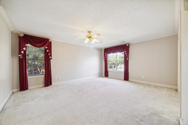 carpeted empty room featuring a textured ceiling, baseboards, a ceiling fan, and crown molding