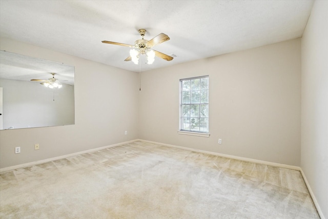 carpeted empty room featuring ceiling fan and baseboards