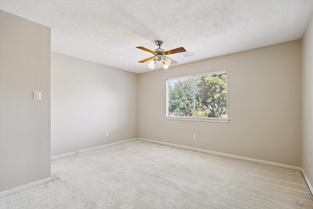 empty room with a textured ceiling, visible vents, a ceiling fan, and carpet flooring