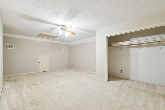 unfurnished bedroom featuring a textured ceiling, visible vents, a closet, carpet, and attic access