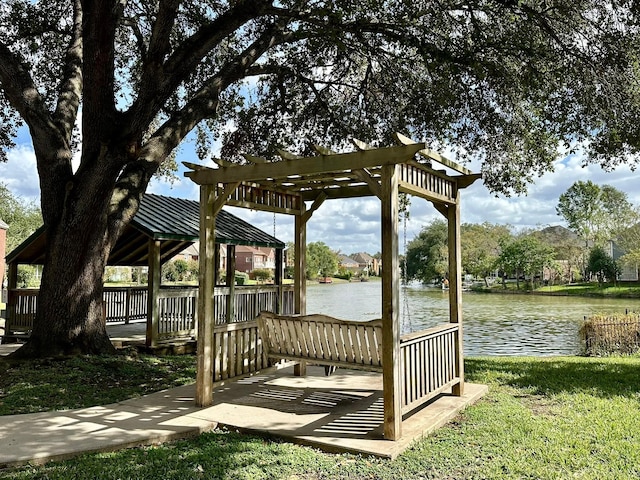 view of dock with a water view, a yard, and a pergola