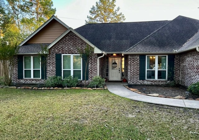 ranch-style house featuring brick siding, a front lawn, and a shingled roof