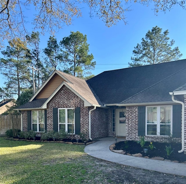 ranch-style house with a shingled roof, brick siding, fence, and a front lawn