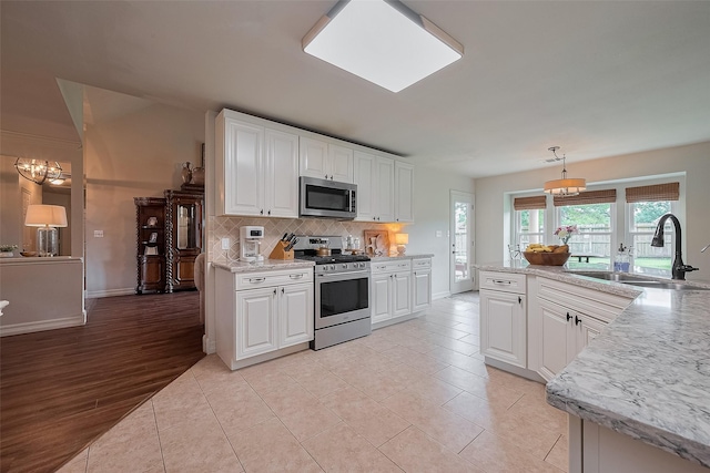 1234 Bergman Ct, Conroe, TX 77384 - kitchen with stainless steel appliances, backsplash, white cabinetry, and a chandelier