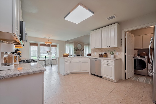 1234 Bergman Ct, Conroe, TX 77384 - kitchen with stainless steel appliances, washer / dryer, white cabinets, and decorative backsplash