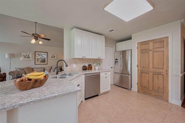 1234 Bergman Ct, Conroe, TX 77384 - kitchen with stainless steel appliances, white cabinetry, open floor plan, decorative backsplash, and a peninsula