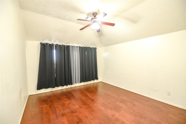 empty room featuring vaulted ceiling, baseboards, and wood finished floors