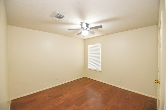 empty room featuring ceiling fan, a textured ceiling, dark wood-type flooring, visible vents, and baseboards