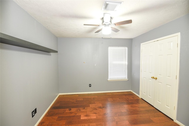 spare room with baseboards, visible vents, ceiling fan, wood finished floors, and a textured ceiling