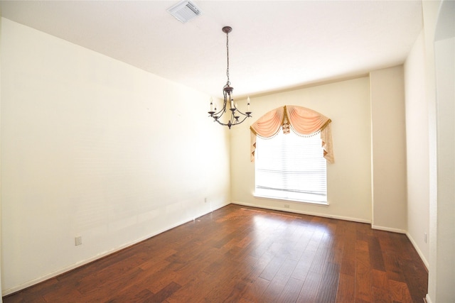 unfurnished room featuring baseboards, wood finished floors, visible vents, and an inviting chandelier