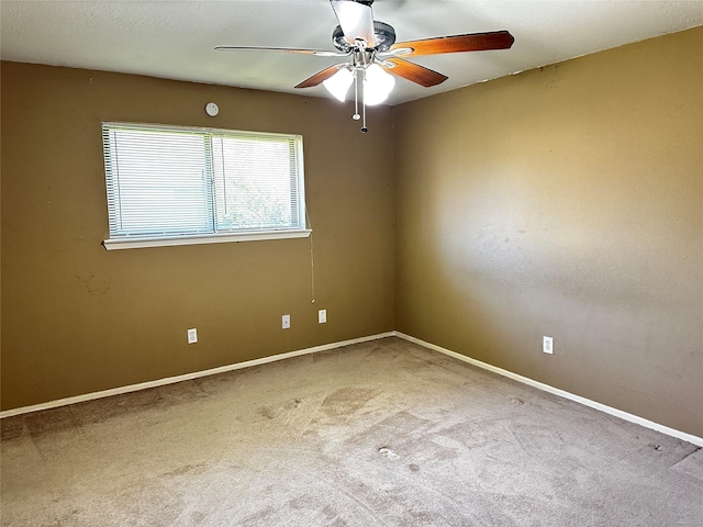 spare room featuring ceiling fan, carpet, and baseboards