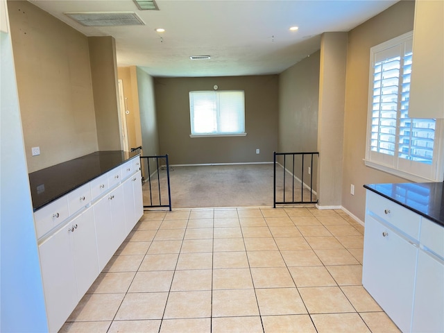 kitchen featuring light tile patterned floors, dark countertops, and visible vents