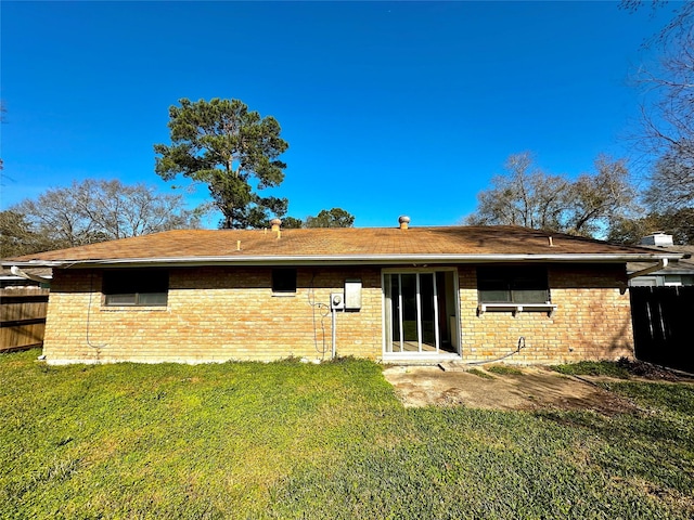 rear view of property featuring brick siding, a lawn, and fence