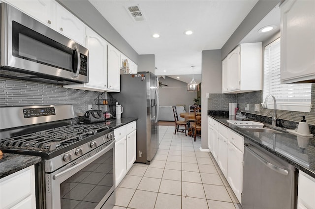 kitchen featuring light tile patterned floors, stainless steel appliances, a sink, visible vents, and white cabinetry