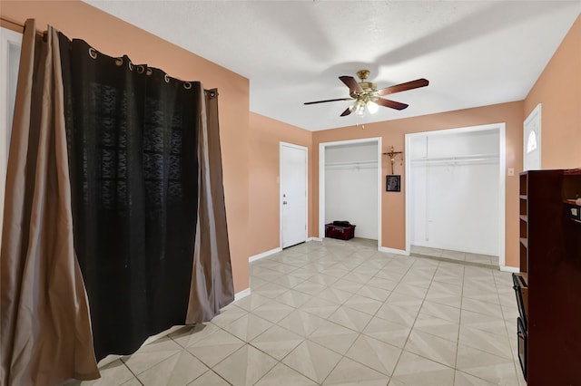 foyer entrance featuring light tile patterned flooring, ceiling fan, and baseboards